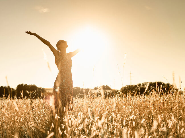 A woman standing in a field with their hands up to the sky