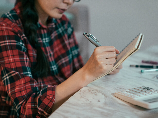 a woman sitting at a desk writing her goals