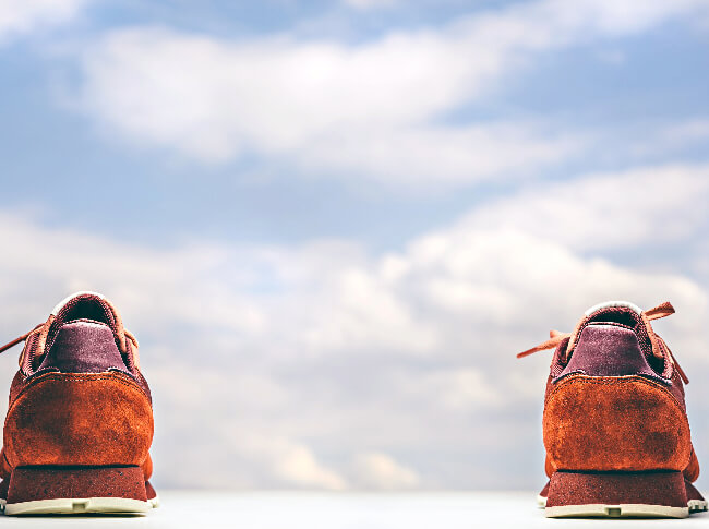Embrace Your Journey: a pair of orange sneakers faced towards a background of clouds