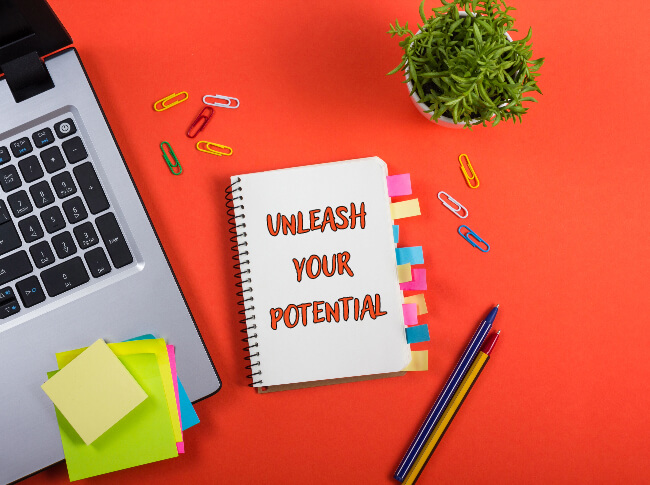 A photo of a desk with a notepad that reads, "Unlease your Potential."