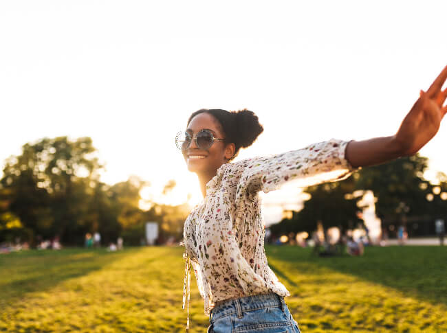 A happy woman with sun glasses looking at the camera while running.
