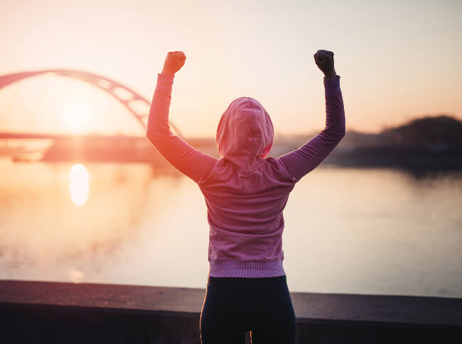 A person looking acrosssome waters with hands up and fists balled.