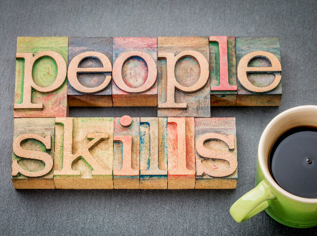 blocks with people skills spelled out and a cup of coffee next to it.