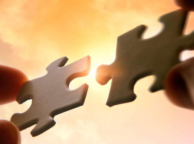 someone putting two pieces of  a puzzel together with a sunny background