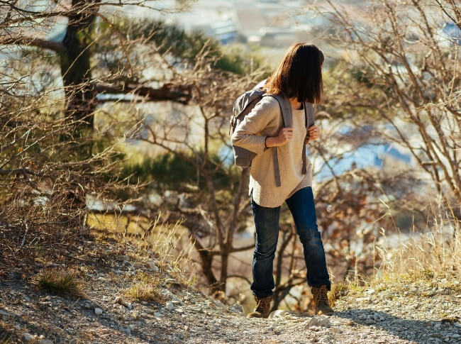 A woman hiking in the woods looking bad